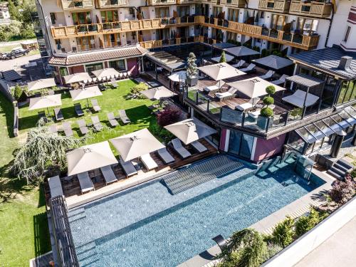 an aerial view of a hotel with a pool and tables and chairs at Tevini Dolomites Charming Hotel in Commezzadura