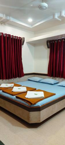 a bed in a room with red curtains at Sai Raghunandan Guest House in Shirdi