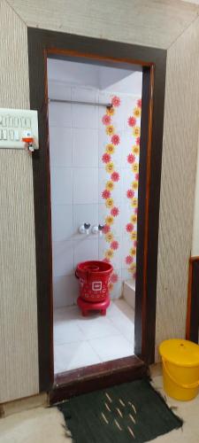 baño con cubo rojo en una habitación en Sai Raghunandan Guest House, en Shirdi