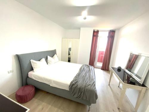ティミショアラにあるGolden Penthouse Rebreanu Residenceのベッドと鏡付きの机がある寝室