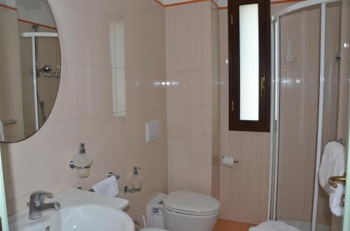 a bathroom with a toilet and a sink and a mirror at Kalos Hotel in Giardini Naxos