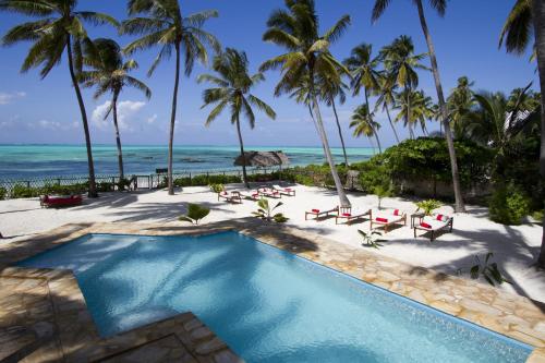 een zwembad op het strand met palmbomen en de oceaan bij Raha Lodge Zanzibar Boutique Hotel in Jambiani