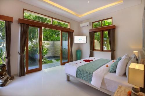 a bedroom with a bed and some windows at Holl Villa by Wildflower Group in Legian