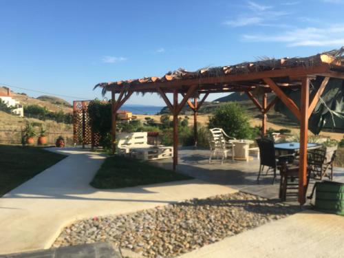 a patio with a table and chairs under a wooden pergola at La casa di Elen in Plati