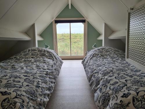 a attic room with two beds and a window at Bed en breakfast Onder aan de dijk in Warder