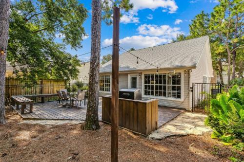 a home with a deck with a table and a grill at Sunrunner Cottage in Pensacola