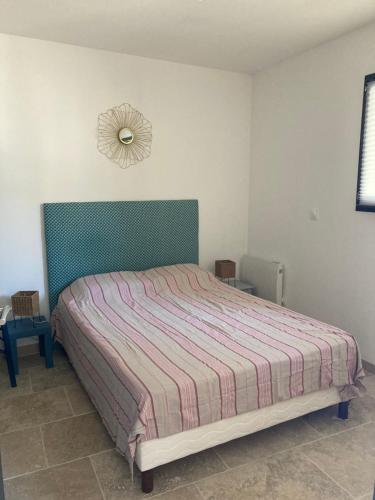 a bedroom with a bed and a clock on the wall at Maisonnette avec jardinet et parking - Velleron in Velleron