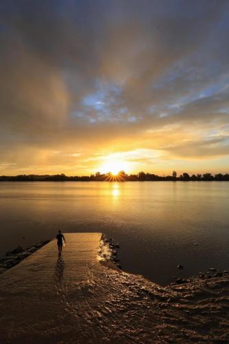 un homme se promenant sur la rive d'un lac au coucher du soleil dans l'établissement Maison Le Mascaret, à Vayres