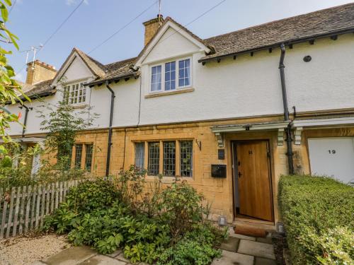 a house with a wooden door and a fence at Blossom Cottage in Broadway