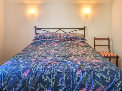 a bed with a blue bedspread with flowers on it at Pear Tree Cottage in Bath