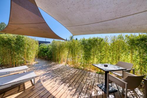 a patio with a table and chairs on a wooden deck at Mas des Cigales in Eygalières