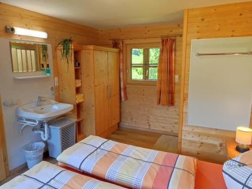 a bathroom with a bed and a sink in a cabin at Ferienwohnungen Schneiderhäusl in Alpbach