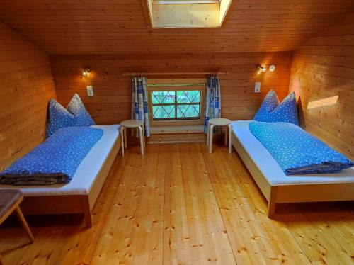 two beds in a room with wooden floors and a window at Ferienwohnungen Schneiderhäusl in Alpbach