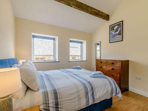 a bedroom with a bed and a dresser and two windows at Courtyard Cottage - Uk39179 in Rossendale