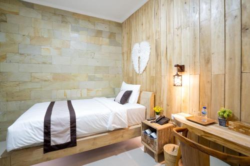 a bedroom with a bed and a wooden wall at Oki Taru Residence in Kuta