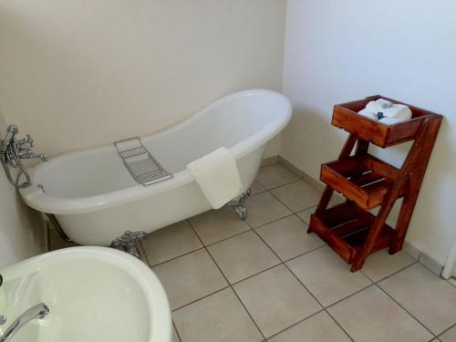 Weaver's Nest Country Inn في Wakkerstroom: حمام مع حوض استحمام ومرحاض ومغسلة