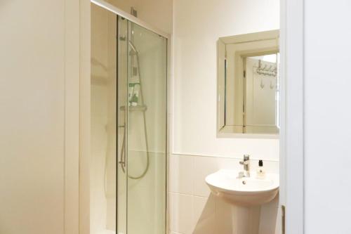 ein Bad mit einer Dusche, einem Waschbecken und einem Spiegel in der Unterkunft Luxurious fully equipped Cowley 1 bed apartment with FREE Parking in Oxford