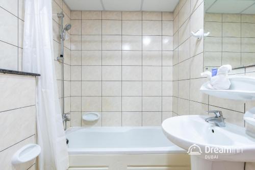 a bathroom with a tub and a sink and a shower at Dream Inn Apartments - Marina Pinnacle in Dubai