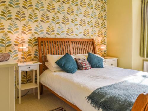 a bedroom with a bed with blue pillows on it at Fell Mount in Grange Over Sands