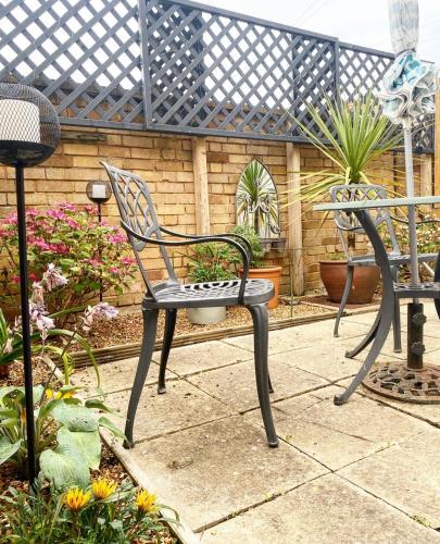 a black chair and a table in a garden at Avocet House Hunstanton 250m from the sea in Hunstanton