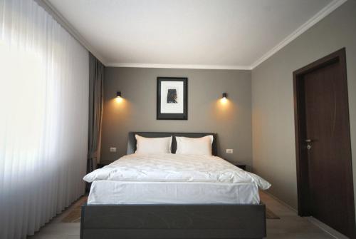 a bedroom with a large bed with white sheets at Hotel Callisto in Pristina
