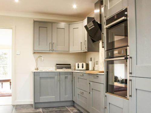 een keuken met witte kasten en roestvrijstalen apparatuur bij Kinness Lodge - Uk39595 in Strathkinness