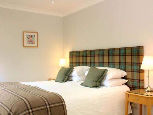 a bedroom with a white bed with two green pillows at Kinness Lodge - Uk39595 in Strathkinness