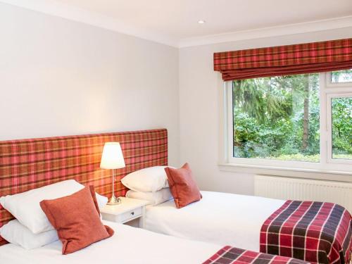 two beds in a room with a window at Kinness Lodge - Uk39595 in Strathkinness