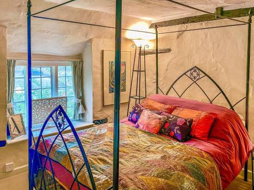 a bedroom with a canopy bed with colorful pillows at Plum Tree Cottage in Fontmell Magna