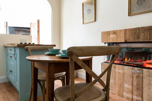 a kitchen with a wooden table and a fireplace at Kylemore House boutique apartments - Fishermans Perch in Kylemore