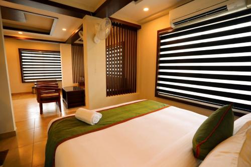 a bedroom with a large white bed and a desk at Zubis Inn Hotel in Kalpetta