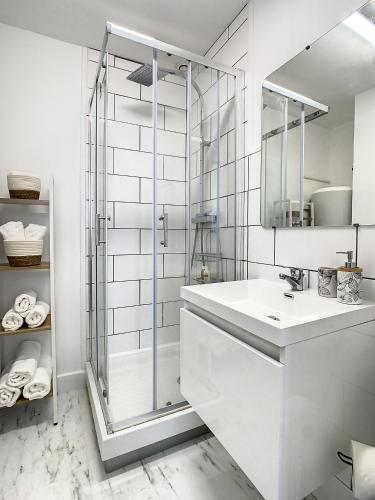 une salle de bain blanche avec une douche et un lavabo dans l'établissement Appartement de charme: La rochelle/vieux port, à La Rochelle