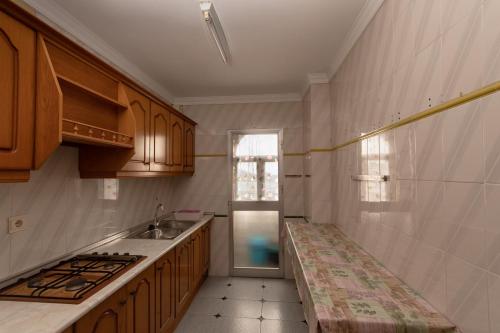 a kitchen with wooden cabinets and a sink and a window at Precioso piso de 3 dormitorios, cocina y 1 baño in Cómpeta