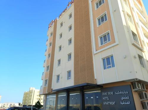 a hotel building with a sign in front of it at Grand Orchid Hotel Apartment in Duqm