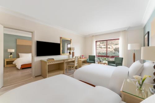a hotel room with two beds and a television at Mövenpick Resort Petra in Wadi Musa