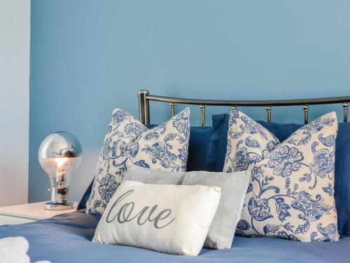 a bed with blue and white pillows and a pillow that says love at Eleanor Cottage in Ballater