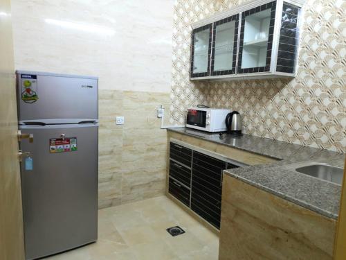 a small kitchen with a refrigerator and a sink at Grand Orchid Hotel Apartment in Duqm