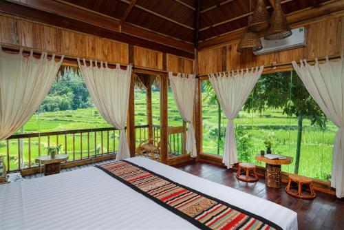 een slaapkamer met een groot bed in een kamer met ramen bij Puluong Luna Resort in Pu Luong