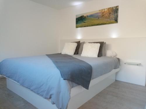 a white bedroom with a bed with blue sheets and pillows at Les hauts de Meez in Dinant