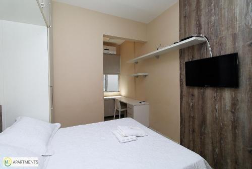 a bedroom with a bed and a flat screen tv at Studio moderno ao lado da praia em Ipanema in Rio de Janeiro