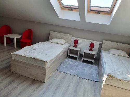 1 dormitorio con 2 camas y silla roja en Stajnia Kruki, en Mrozy