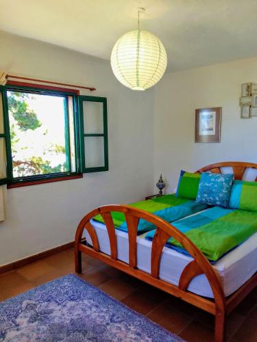 a bedroom with a bed with green and blue pillows at Casa Flor azul in Las Tricias