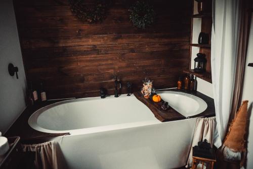 y baño con bañera blanca y paredes de madera. en Kociewski Raj, en Godziszewo