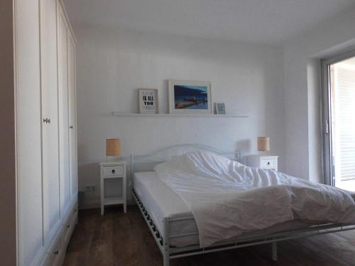 ein weißes Schlafzimmer mit einem Bett und zwei Nachttischen in der Unterkunft Smart Loft in Bad Pyrmont