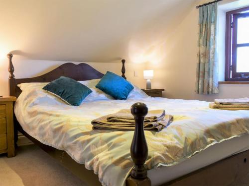 a bedroom with a large bed with blue pillows at Crofters Barn in Brentor