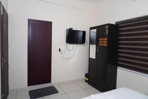 een kamer met een deur en een tv aan de muur bij Atmos Inn in Kozhikode