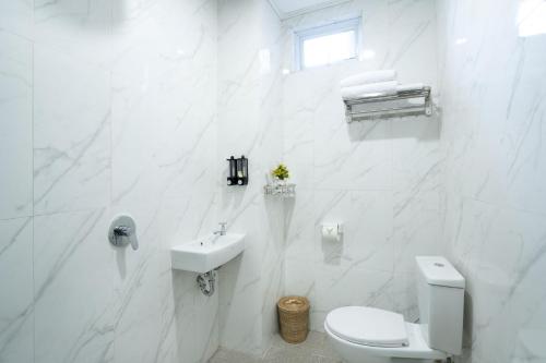La salle de bains blanche est pourvue de toilettes et d'un lavabo. dans l'établissement Oki Taru Residence, à Kuta