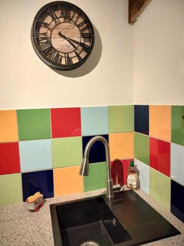 a clock on the wall above a kitchen sink at Chambre d'hôtes La terrasse de Sabatas in Chomérac