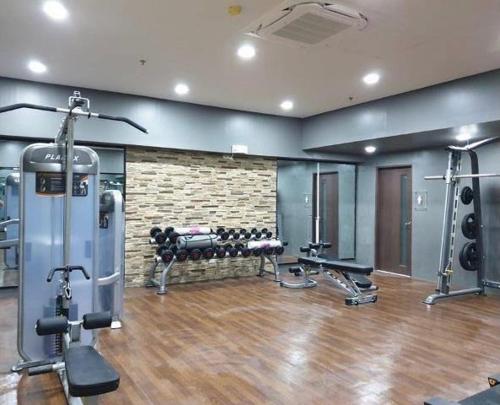 a gym with several treadmills and machines in a room at Luxury Suites at Brenthill Baguio City in Baguio
