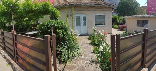 a wooden fence in front of a house with flowers at CASA DIDINA fosta Pensiune Casa Didina in Bacău